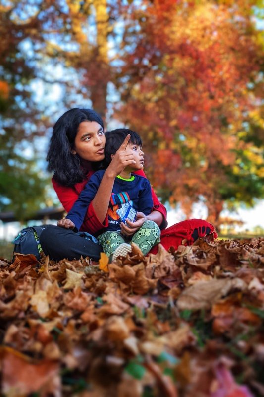 Woman with a small boy sitting in autumn leaves